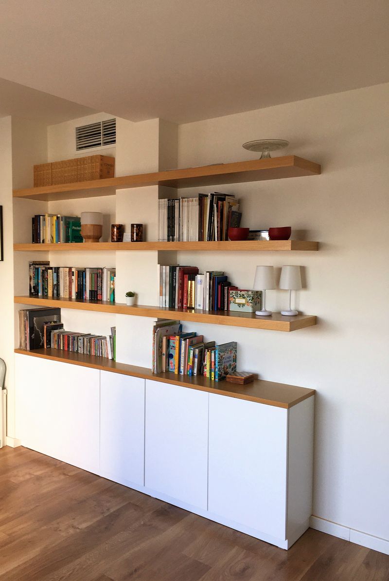 Una librería blanca con libros y una imagen de un libro en la pared.